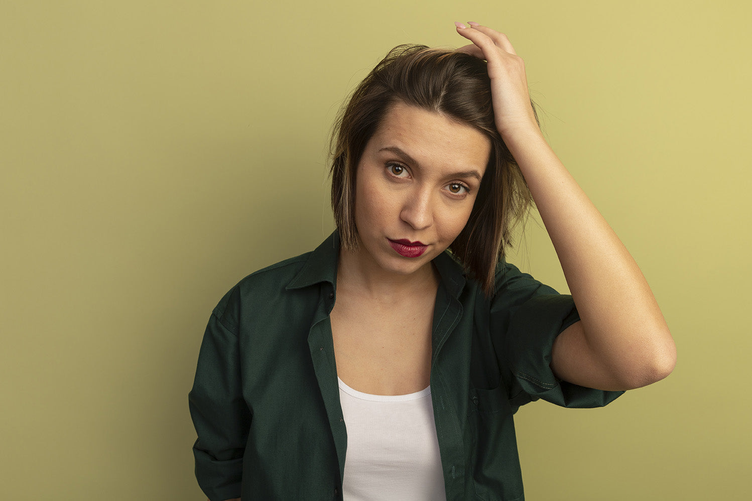 confident-pretty-woman-puts-hand-head-looking-front-isolated-olive-green-wall_1.jpg